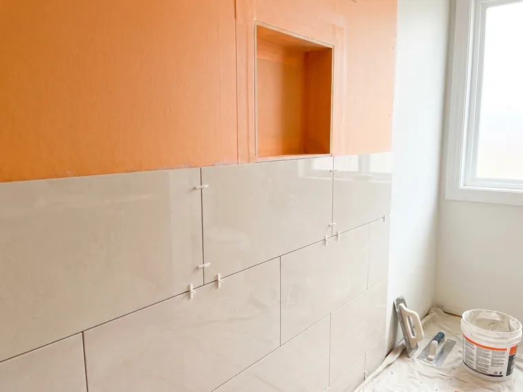 Shower wall with orange waterproofing membrane and tile going up
